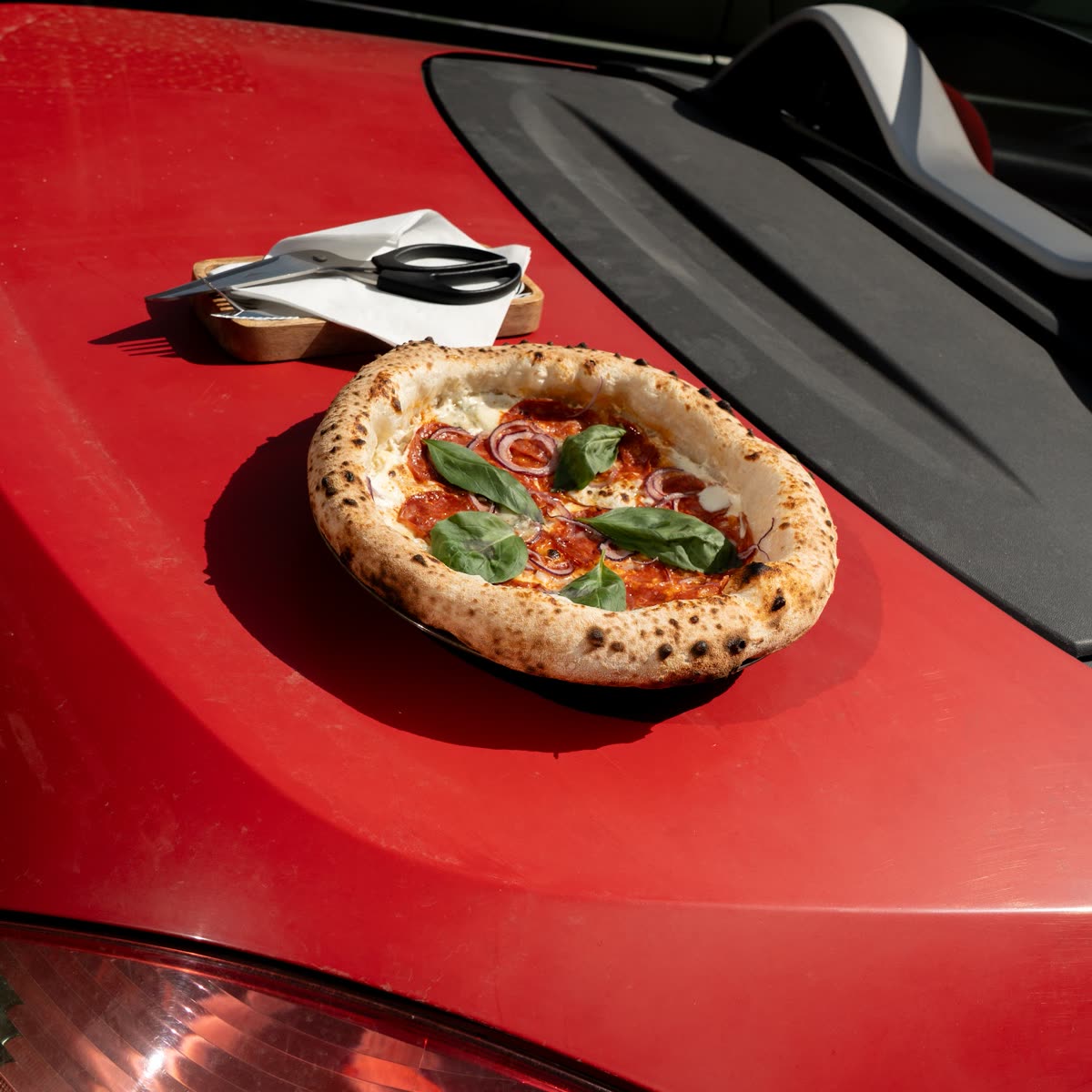 Neapolitan pizza on the bonnet of a red car